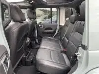 Vue intérieure arrière côté droit de la Jeep Wrangler Unlimited 2023, sièges en cuir noir et finitions modernes visibles.