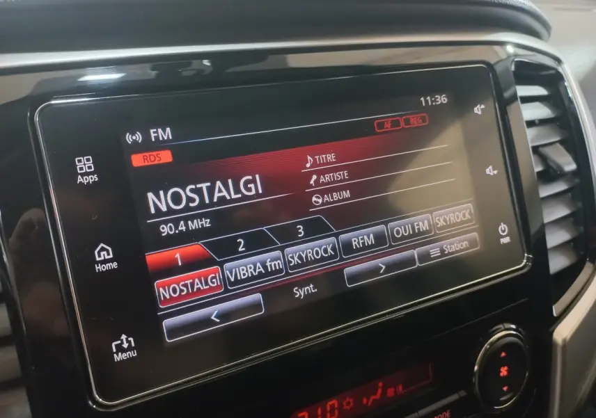 Écran tactile central du tableau de bord du Mitsubishi L200 gris foncé, affichant la radio FM sur Nostalgie.