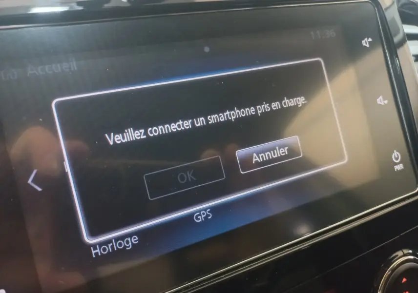 Écran tactile central du Mitsubishi L200 gris foncé affichant un message de connexion smartphone en intérieur véhicule.