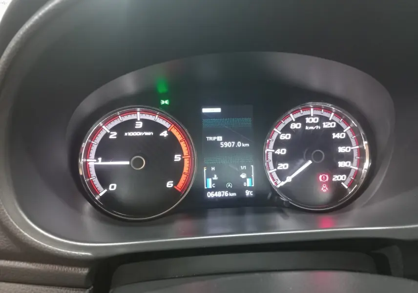 Tableau de bord du Mitsubishi L200 gris foncé 2020, affichage digital central et compte-tours à gauche, compteur de vitesse à droite.