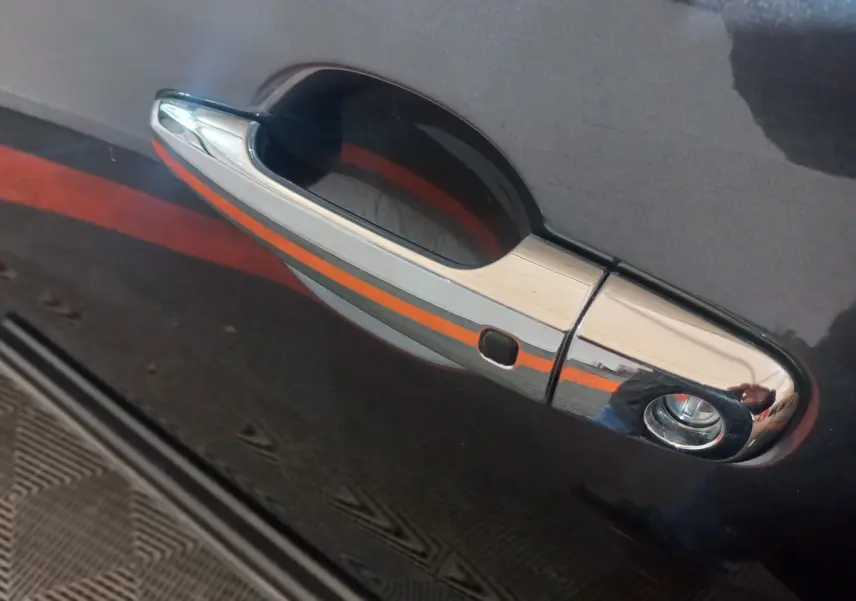 Poignée de porte chromée sur la portière gris foncé d’un Mitsubishi L200, vue en gros plan côté gauche.