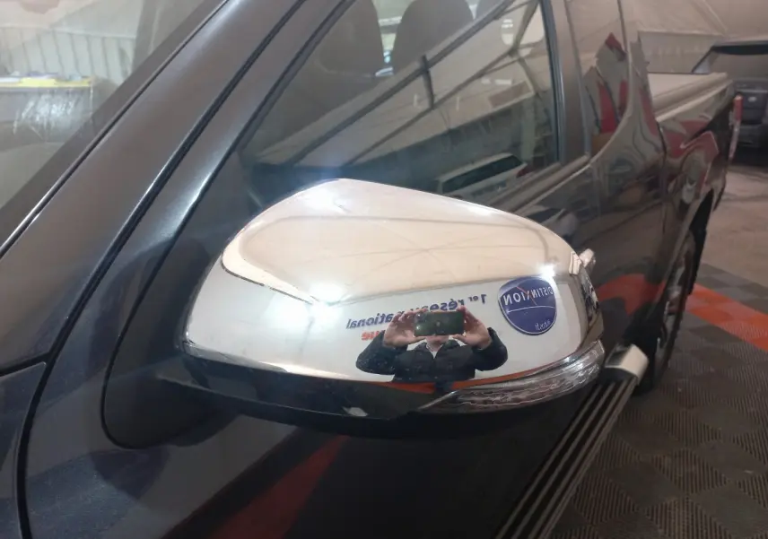 Rétroviseur droit chromé du Mitsubishi L200 gris foncé, vue rapprochée sur la porte avant côté conducteur.