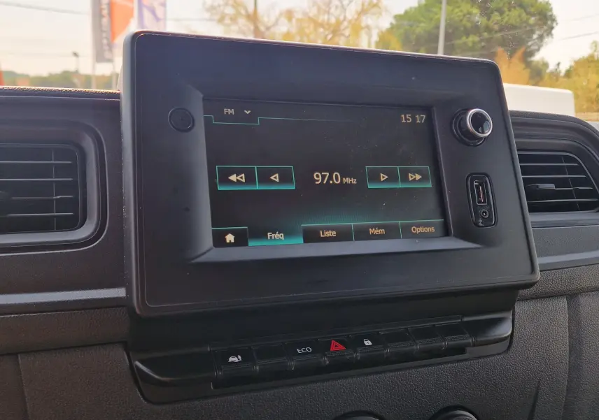 Écran tactile central du tableau de bord du Renault Master blanc, affichant une radio FM à 97.0 MHz.