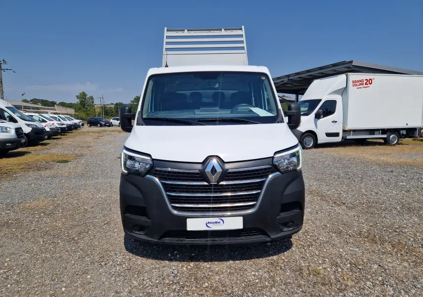 Vue de face d’un utilitaire Renault Master blanc avec benne aluminium et coffre, sur un terrain extérieur ensoleillé.