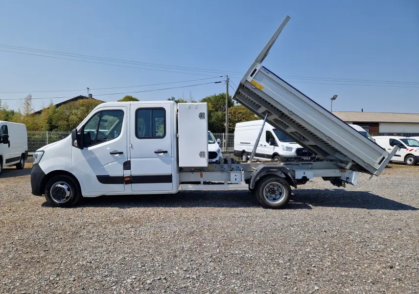 Vue latérale droite d’un Renault Master blanc avec benne aluminium relevée et coffre latéral blanc fixé derrière la cabine double.