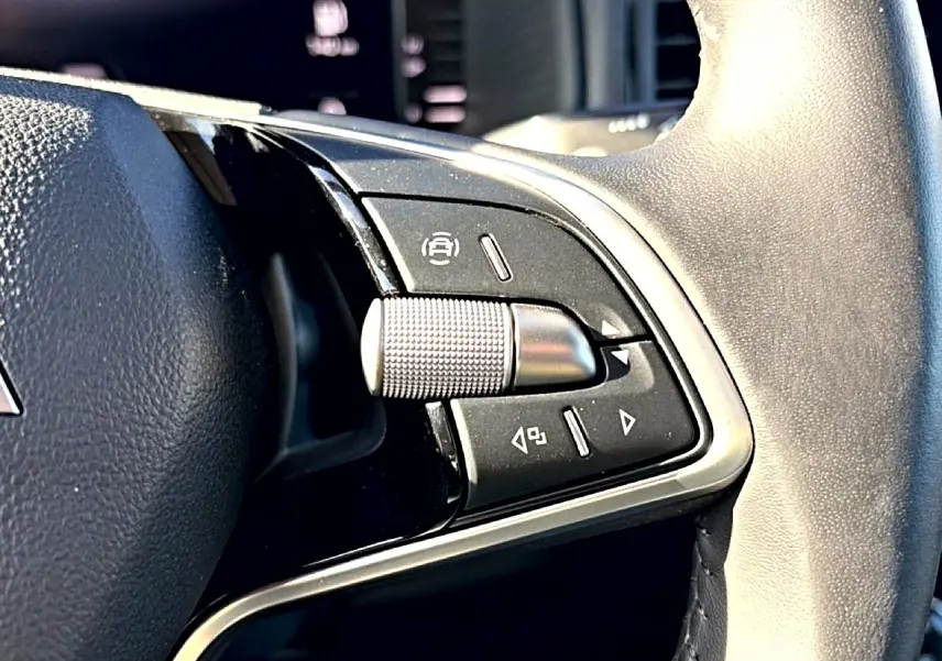 Gros plan sur les commandes noires et argent du volant cuir du Skoda Karoq gris, version 1.5 TSI 2025.