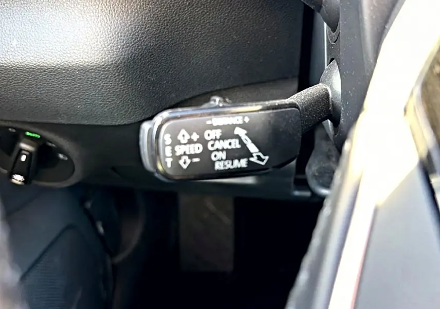 Gros plan sur le commodo de régulateur de vitesse dans l’habitacle noir d’un Skoda Karoq gris 2025.