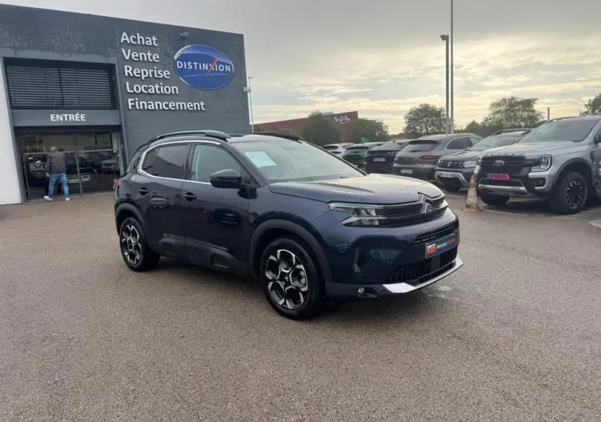 Citroën C5 Aircross hybride bleu foncé vue 3/4 avant droit avec barres de toit et jantes alliage 18 pouces.