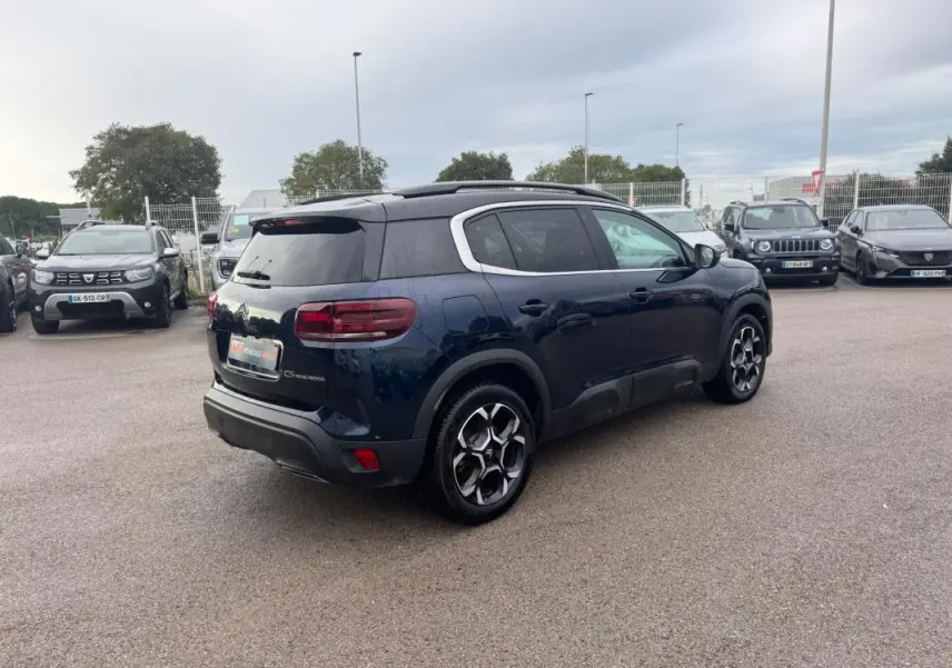 Citroën C5 Aircross bleu foncé vue 3/4 arrière droit avec barres de toit et jantes alliage 18 pouces.
