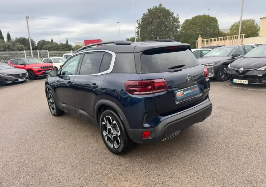 Vue 3/4 arrière droite d’un Citroën C5 Aircross bleu foncé avec barres de toit et jantes alliage 18 pouces.