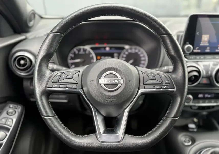 Volant en cuir noir de Nissan Juke 2023 avec commandes intégrées, tableau de bord et écran tactile en arrière-plan.