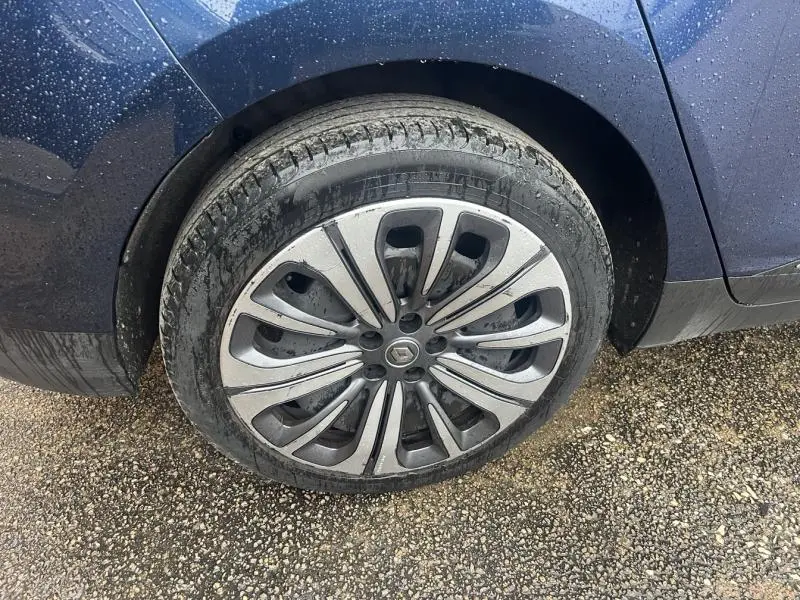 Gros plan sur la roue avant gauche d’un Renault Grand Scenic bleu Cosmos avec jante alu au design moderne.