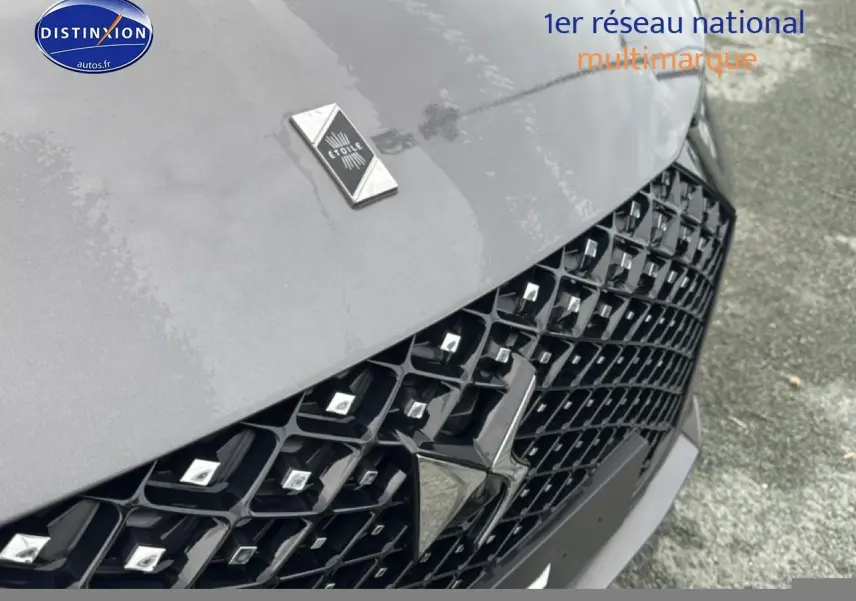 Gros plan sur la calandre noire et le capot gris platinium du DS4 Hybride 145 Pallas 2024 avec logo DS étoile.