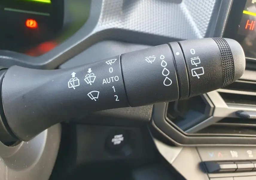 Gros plan sur la commande d’essuie-glace du tableau de bord du Dacia Duster 2026 vert cèdre, intérieur noir.