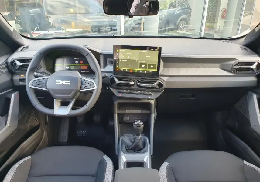 Vue intérieure avant du Dacia Duster 2026 avec tableau de bord moderne, écran tactile et volant multifonction.