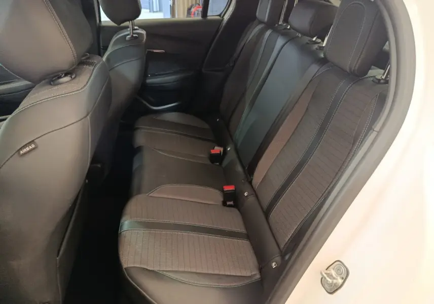 Vue côté droit de la banquette arrière noire et grise du Peugeot 208 blanc, avec appuie-têtes et ceintures visibles.