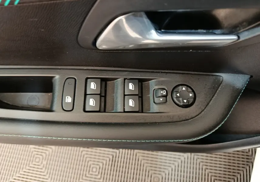 Vue rapprochée du panneau de commandes des vitres et rétroviseurs côté conducteur d'une Peugeot 208 blanche, intérieur noir.