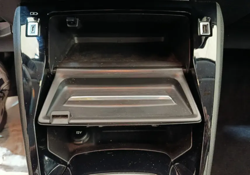 Vue rapprochée de la console centrale noire de la Peugeot 208 avec compartiment ouvert et ports USB visibles.