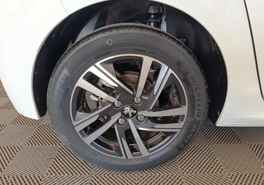 Gros plan sur la roue avant gauche de la Peugeot 208 blanche, avec jante alliage et pneu Michelin.