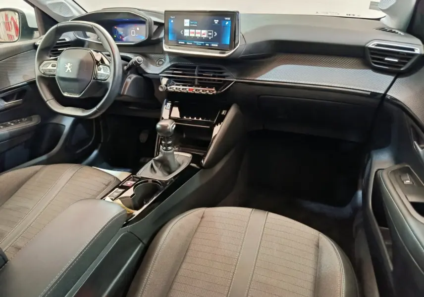 Intérieur avant droit de la Peugeot 208 PureTech 100 blanc, tableau de bord avec écran tactile 10 pouces et boîte manuelle.