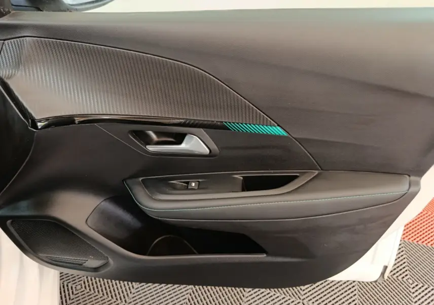 Vue rapprochée de la porte intérieure côté gauche d’une Peugeot 208 blanche avec surpiqûres bleues et insert décoratif.