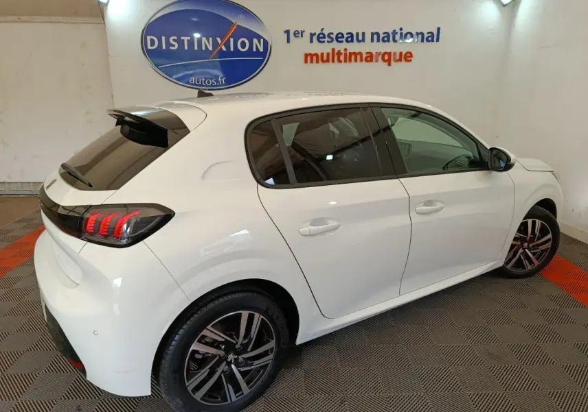 Peugeot 208 blanc vue 3/4 arrière droit, feux arrière à griffes LED et jantes alliage noires visibles.