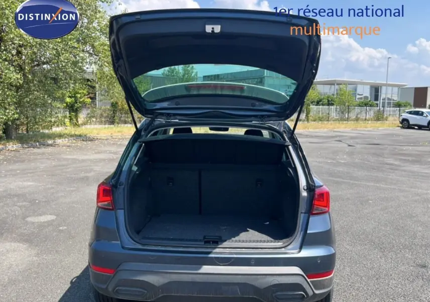 Vue arrière d'un SEAT Arona gris Magnetic avec coffre ouvert, montrant l'espace de chargement vide en extérieur.