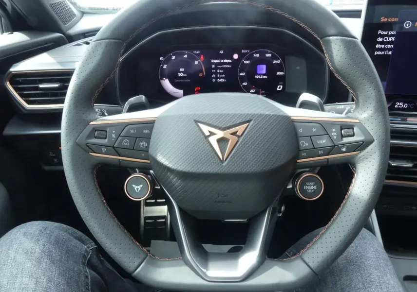 Vue rapprochée du volant perforé noir avec surpiqûres cuivrées et tableau de bord digital du CUPRA Formentor gris magnétique 2025.