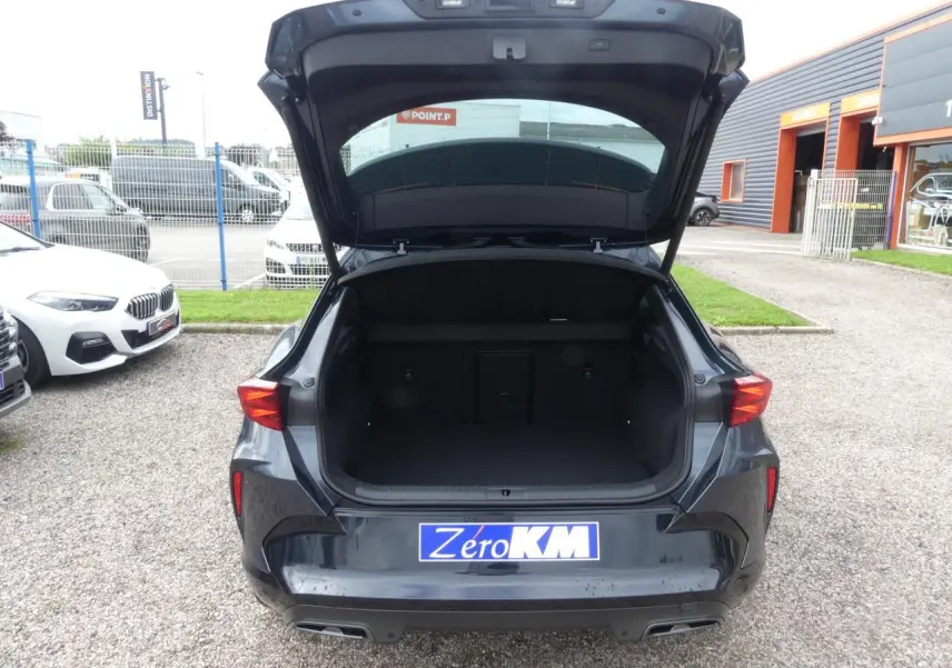 Vue arrière du CUPRA Formentor gris magnétique 2025 avec coffre ouvert et feux arrière allumés dans un parking.