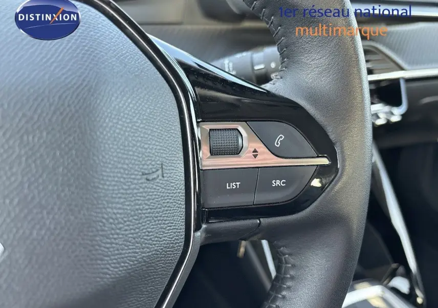 Gros plan sur les commandes au volant en cuir noir du Peugeot 2008 gris Artense, version 1.2 PureTech 130 Active de 2021.