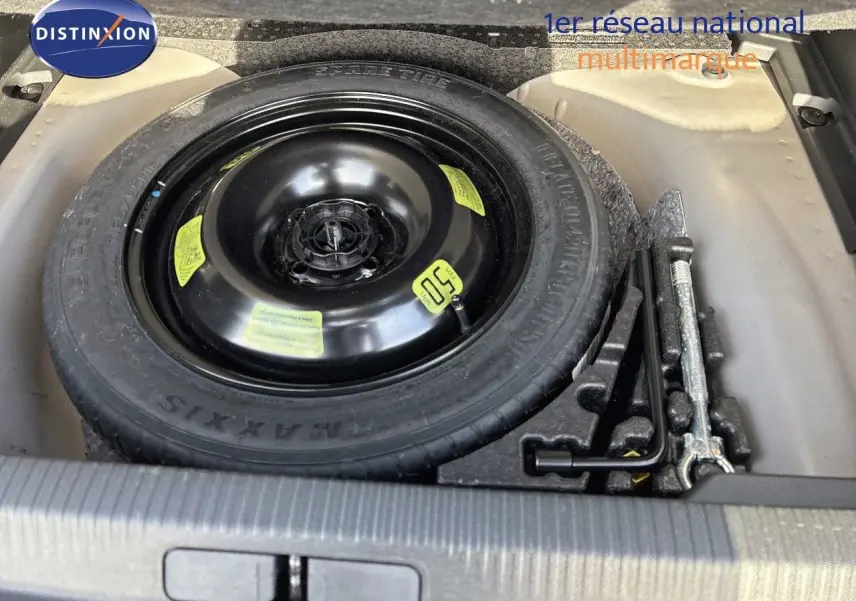 Roue de secours noire et outils de changement dans le coffre d'un Peugeot 2008 gris Artense 2021.