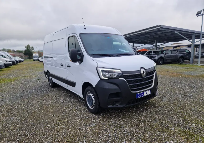 Renault Master blanc en vue 3/4 avant droit sur parking, avec calandre noire et hayon arrière visible.