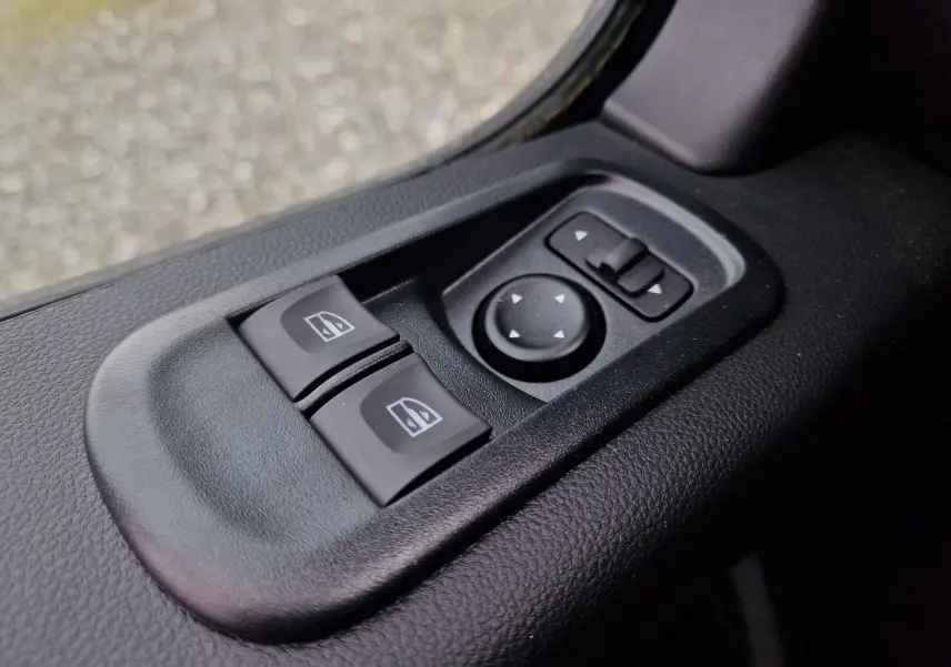 Commandes électriques des vitres et réglage des rétroviseurs sur la porte intérieure côté conducteur d'un Renault Master blanc 2023.