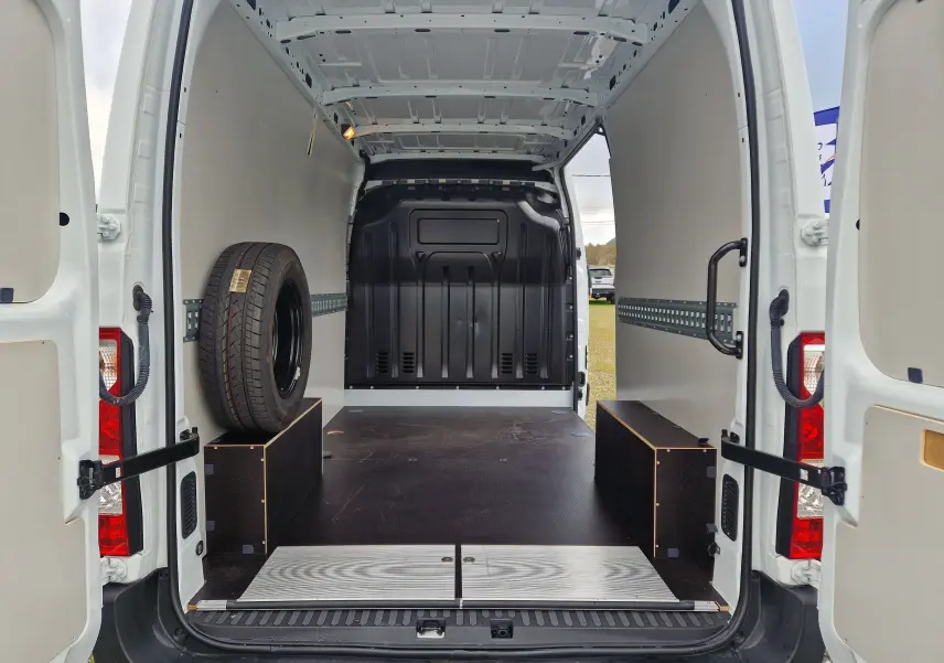 Vue arrière intérieure du Renault Master blanc 2023 avec hayon ouvert et aménagement bois dans l’espace de chargement.