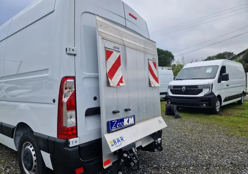 Vue arrière gauche d'un Renault Master blanc 2023 avec hayon élévateur et un autre Master blanc en arrière-plan côté droit.