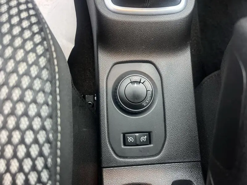 Vue plongeante sur la commande de mode 4x4 et boutons d'assistance entre les sièges avant du Dacia Duster gris Comète.