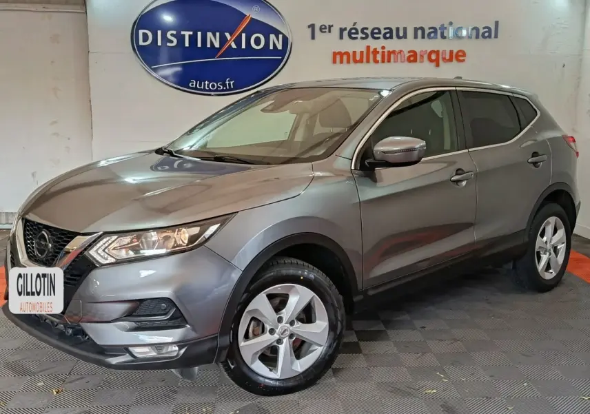 Nissan Qashqai gris clair en 3/4 avant droit, SUV compact avec phares LED et jantes alliage visibles.