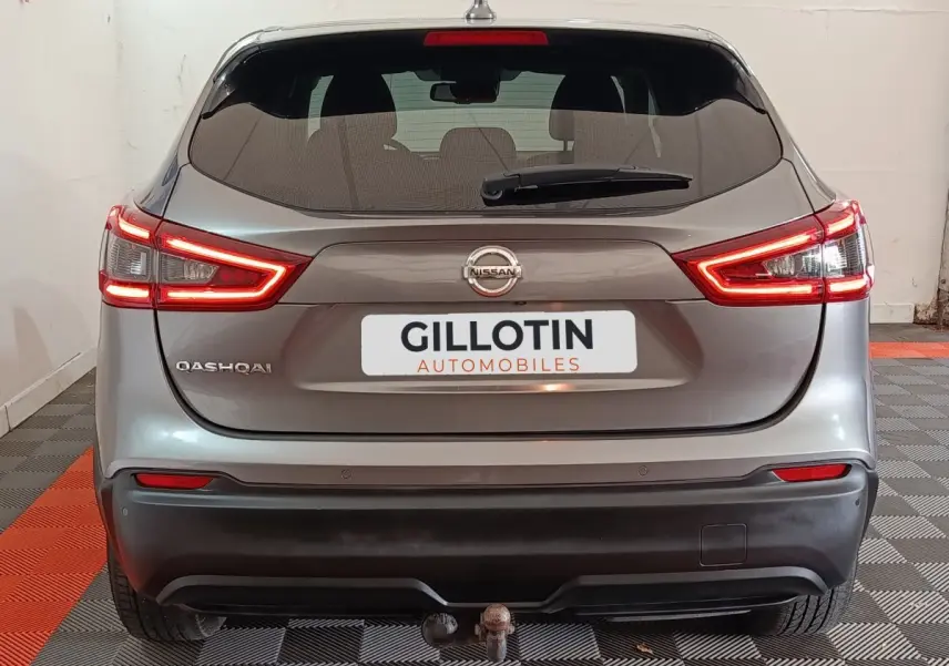 Vue arrière d'un Nissan Qashqai gris clair 2019 avec feux LED allumés et attelage visible.