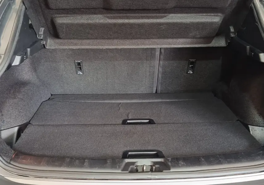 Coffre ouvert du Nissan Qashqai gris clair, vue de l'arrière montrant la surface de chargement et la tablette de séparation.