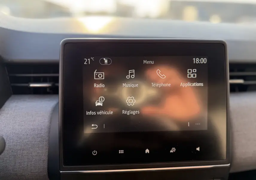 Écran tactile central de la Renault Clio V gris schiste, affichant le menu principal avec options radio, musique et téléphone.