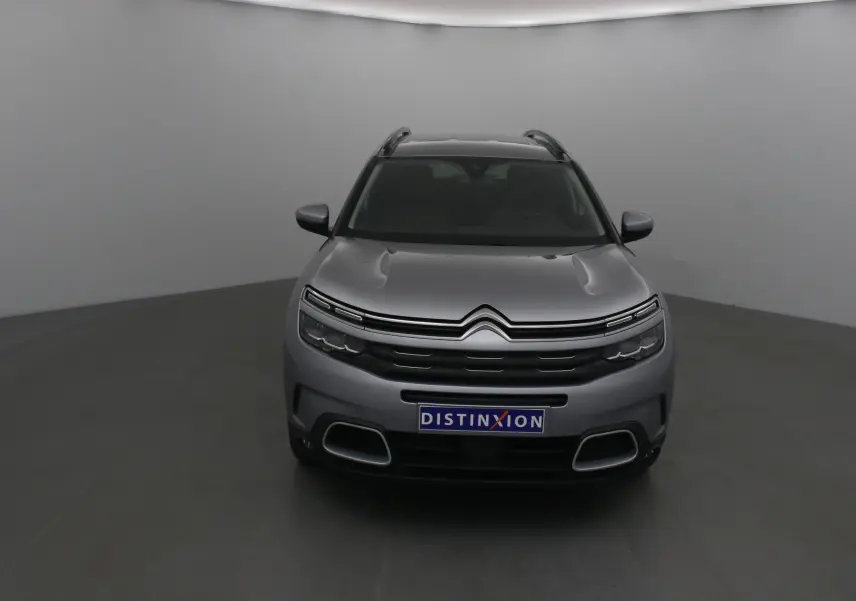 Vue frontale d'un Citroën C5 Aircross gris Artense avec calandre distinctive et plaque Distinxion visible.