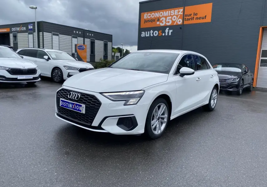 Audi A3 Sportback blanc Ibis vue 3/4 avant droit avec calandre noire et jantes alliage 18 pouces sur parking humide