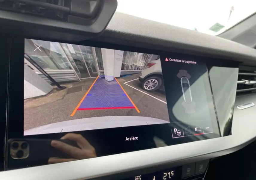 Vue de l'écran de caméra de recul de l'Audi A3 Sportback blanche, montrant l'arrière et les lignes de guidage du stationnement.