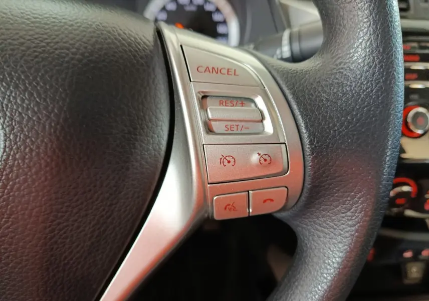 Gros plan sur les commandes multifonctions argentées du volant noir du Nissan Navara gris clair, version Acenta 2018.