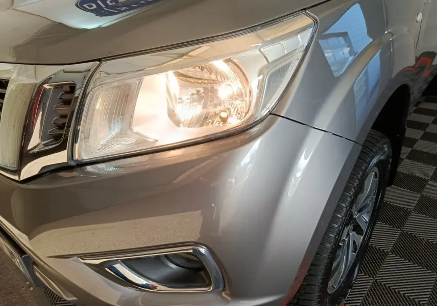 Gros plan sur l'avant droit gris clair du Nissan Navara 2018 avec phare allumé et jante visible.