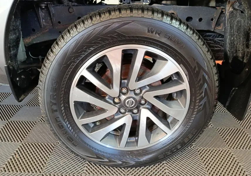 Gros plan sur la roue avant droite du Nissan Navara gris clair, jante alliage à plusieurs branches distinctives.