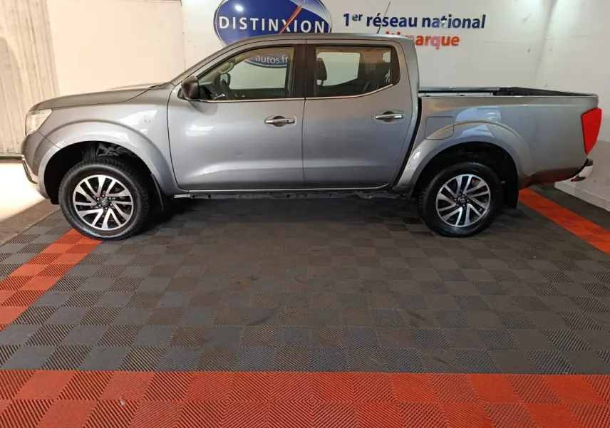Vue de profil côté gauche d'un Nissan Navara Double-Cab gris clair avec benne pick-up et jantes alliage.