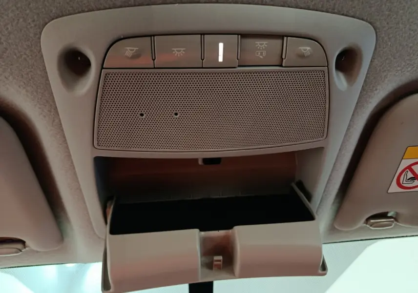 Vue intérieure en plongée du compartiment lunettes ouvert et des commandes d'éclairage au plafond du Nissan Navara gris clair.