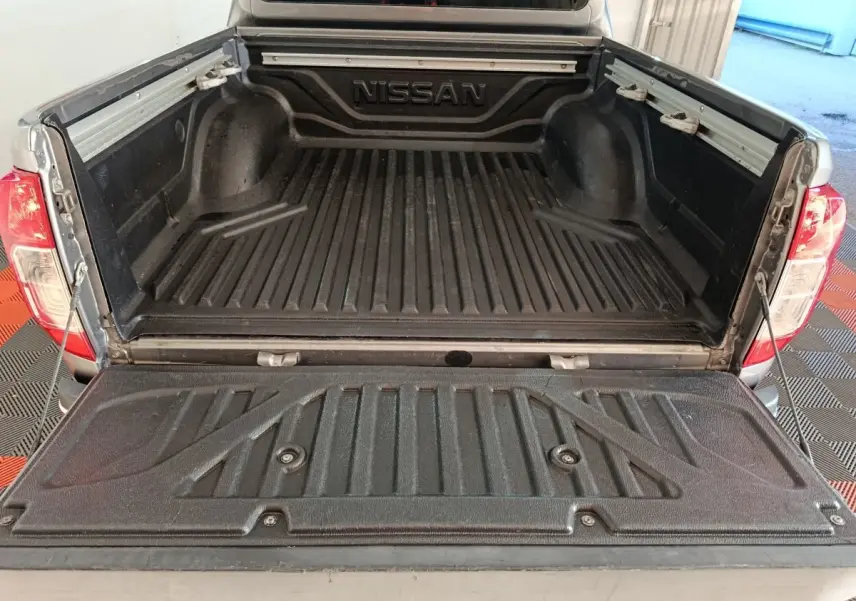 Vue arrière du pick-up Nissan Navara gris clair 2018 avec benne ouverte et revêtement noir antidérapant.