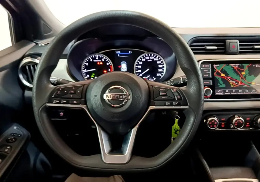 Vue intérieure centrée sur le volant multifonctions noir d’une Nissan Micra 2020 avec tableau de bord et écran tactile de navigation.